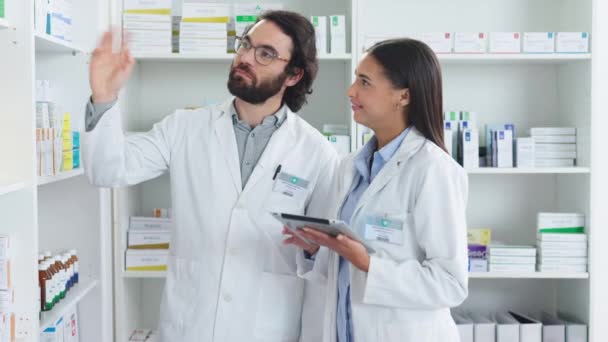 Pharmacists working together stocktaking medication at the pharmacy. Two healthcare professionals discussing a patient prescription at a dispensary. Two medical doctors talking about medicine tablets. - Záběry, video