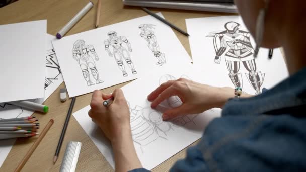 A woman artist draws on paper sketches of a storyboard of robots, cyborgs. - Video, Çekim