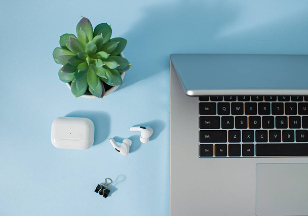 Creatieve kantooromgeving en werksfeer voor thuiswerken. Koffie, laptop, telefoon en koptelefoon op pastelblauwe bureauachtergrond. - Foto, afbeelding