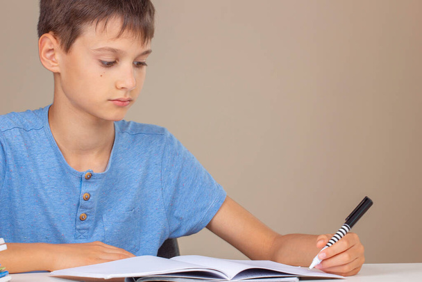 Niño sosteniendo la pluma en la mano izquierda y escribiendo en un cuaderno, haciendo la tarea. Día de los zurdos. - Foto, imagen