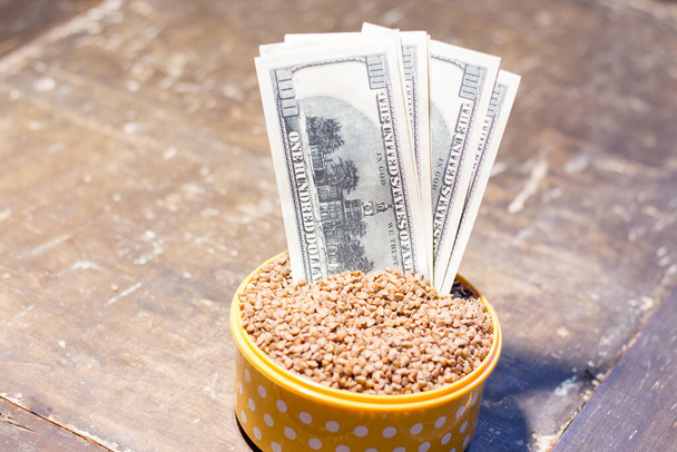 Banknotes in a bowl with buckwheat. The rise in food prices in Ukraine due to the war - Photo, Image