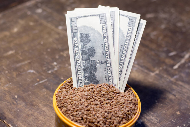 Banknotes in a bowl with buckwheat. The rise in food prices in Ukraine due to the war - Photo, Image