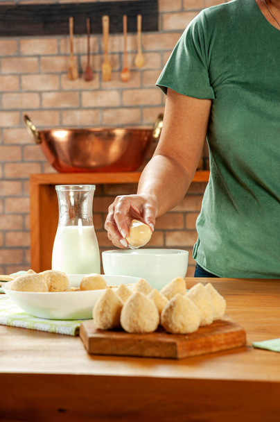 Dłonie kobiety pieczone brazylijska krokieta (coxinha de frango) na drewnianym stole. - Zdjęcie, obraz