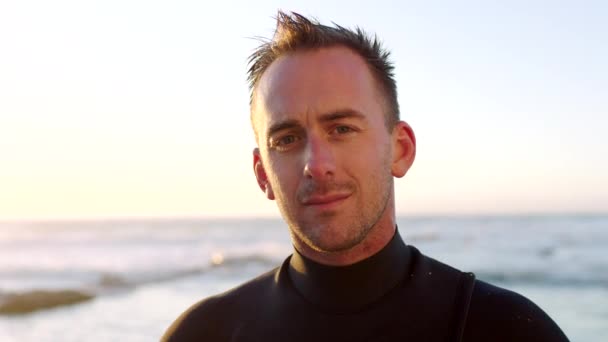 Portrait of a handsome male surfer in a wetsuit by the beach. Mature man waiting for the current, tide and waves to surf in the sea. Enjoying his recreational hobby time by the ocean. - Séquence, vidéo