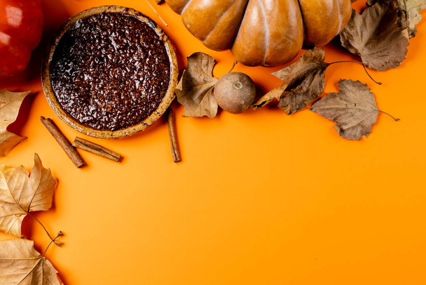 Composition of pumpkins, autumn leaves, cinnamon and pie on black background. Halloween, autumn, tradition and celebration concept. - Foto, immagini