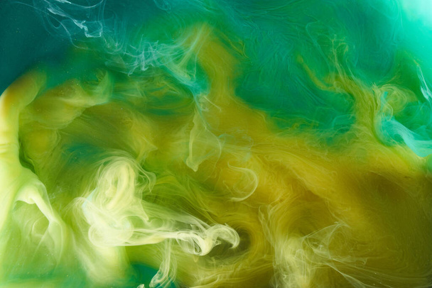 Liquid fluid art abstract background. Green, yellow dancing acrylic paints underwater, space smoke ocean, color explosion - Фото, изображение