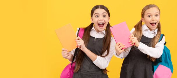 School girls friends. Happy children in formal school uniforms hold study books yellow background, knowledge day. Banner of schoolgirl student. School child pupil portrait with copy space - Foto, Imagem