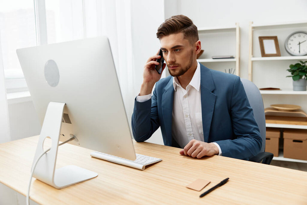 Ein Mann im Anzug am Schreibtisch im Büro mit offiziellem grauen Hintergrund. Hochwertiges Foto - Foto, Bild
