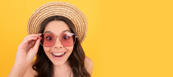surprised kid in summer straw hat and glasses has curly hair on yellow background, summer sales. Child face, horizontal poster, teenager girl isolated portrait, banner with copy space - Photo, image