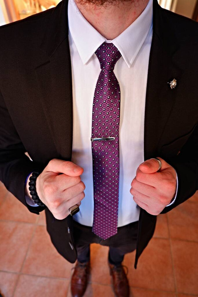 Hände regulierendes Sakko, weißes Hemd und lila Krawatte mit Krawattenclip. - Foto, Bild