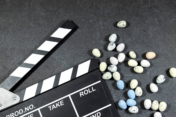 clapper board of video cinema in studio with easter eggs on grunge gray background - Fotó, kép