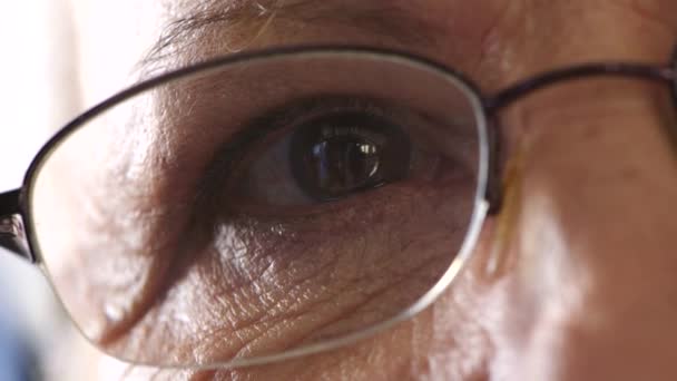 Egy nyugdíjas férfi arcának részletei, aki boldog, nosztalgikus emlékekre gondol. Idősebb férfi szemüvegben. Egy olvasó szemüveggel vagy szemüveggel rendelkező idős személy közelsége látás és látásjavítás céljából. - Felvétel, videó
