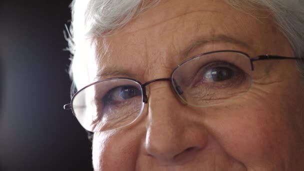 Ritratto di una donna anziana che guarda con speranza all'umanità. Primo piano di una nonna con occhiali da lettura per la correzione della vista. Volto e occhi di una saggia signora che pensa a un ricordo felice e sogna ad occhi aperti. - Filmati, video