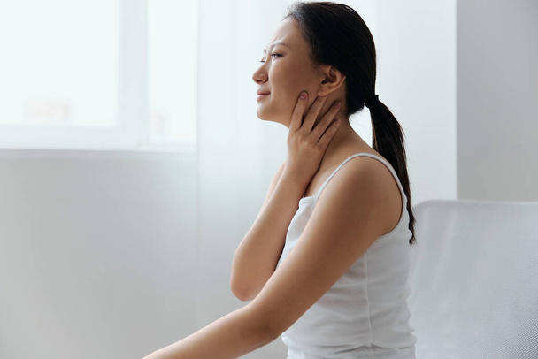 Tickling Cough. Side view of suffering crying tanned beautiful young Asian woman touch neck sore throat at home interior living room. Injuries Poor health Illness concept. Cool offer Banner - Photo, Image