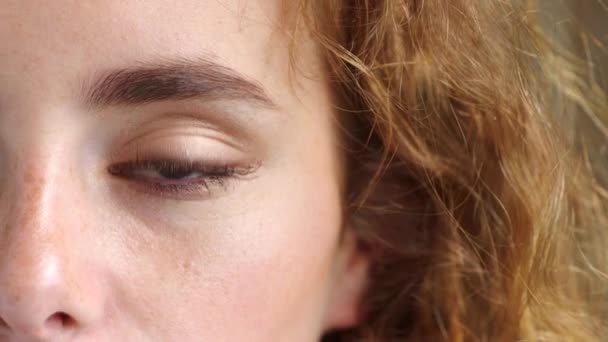 Close-up van een vrouw die haar zicht en gezichtsvermogen test bij de optometrist. Vrouw met rood haar en sproeten knipperend terwijl ze met haar blauwe ogen naar de camera staart. Bewust kijken met geïnspireerde ideeën. - Video