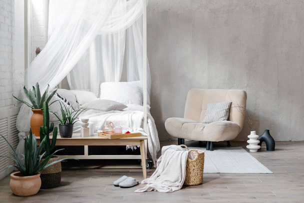 Yatak odası yatak örtüsü, beyaz yatak örtüsü, yastıklar, koltuklar, ev dekorasyonu ve ahşap bankta çiçek saksıları olan sulu ev bitkileri. İskandinav iç tasarımı - Fotoğraf, Görsel