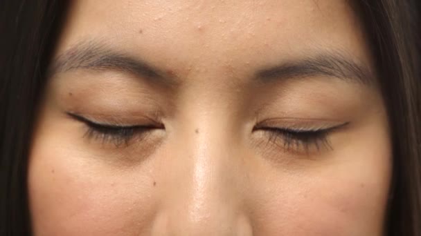 Closeup portrait of human eyes blinking and looking awake and aware while gazing at the camera. Headshot, face and skin detail of a happy asian woman staring and feeling positive and content. - Metraje, vídeo