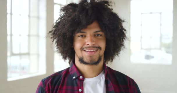 Headshot of a happy male with a beard looking calm and friendly. Portrait of a young and stylish man smiling and looking joyful. One trendy and smiling guy with an afro relaxing and looking cheerful. - Filmmaterial, Video