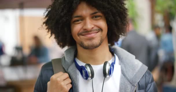 Модный афроамериканец улыбается в городском городке. Портрет молодого и уверенного африканского студента, наслаждающегося отдыхом на свежем воздухе в современном городе или кампусе. - Кадры, видео