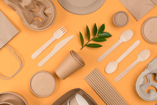Flat lay style image with eco-friendly tableware - kraft paper food packaging over orange background. Street food paper packaging, recyclable paperware, zero waste packaging concept - Foto, Bild