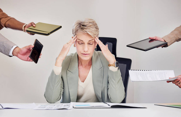зрелая деловая женщина, сидящая в офисе и испытывающая стресс, в то время как ее коллеги давят на нее. - Фото, изображение