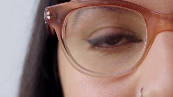 Mujer mirando o mirando con gafas de visión de optometría de moda. Primer plano de los ojos mirando hacia adelante mientras usa gafas ópticas recetadas. Detalle de la señora con maquillaje delineador de ojos y cosméticos rímel. - Metraje, vídeo