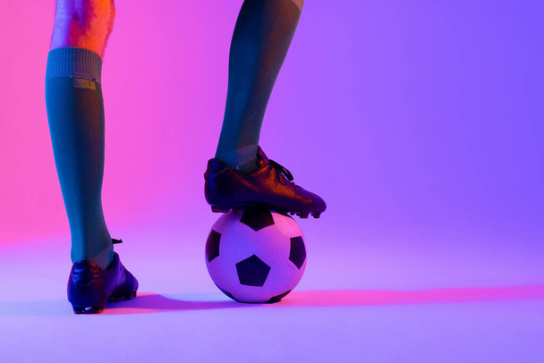 Caucasian male soccer player with football over neon pink lighting. Sport, movement, training and active lifestyle concept. - Φωτογραφία, εικόνα
