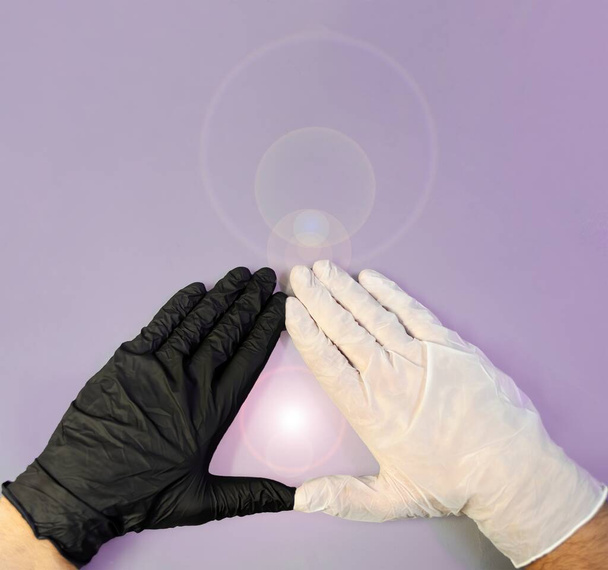Hands with black and white gloves, united to form a triangle and in the center a soft luminous flash on a violet background, healing energy, triangular shaped energy field with plenty of copy space - Photo, Image