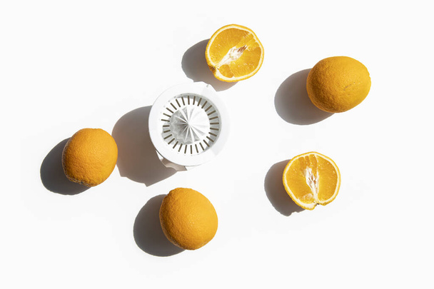 Свежие апельсины, приготовленные для сока в миске для рук на белом фоне. Вид сверху, плоский. - Фото, изображение