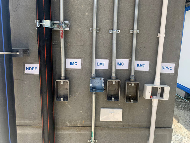 Viele Rohr- und Lichtschalter montieren an grauen oder grauen Wänden wie HDPE, IMC, EMT und PVC. Elektrische, Wassergasleitung auf Baustelle. - Foto, Bild