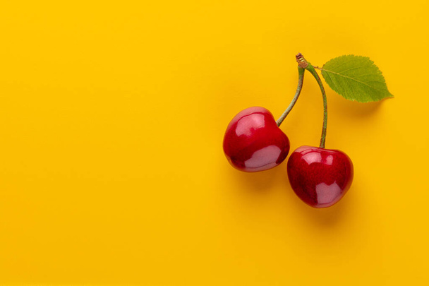 Cherry berries on a pastel background top view.  Background with a cherry on a sprig, flat lay - Foto, Imagen