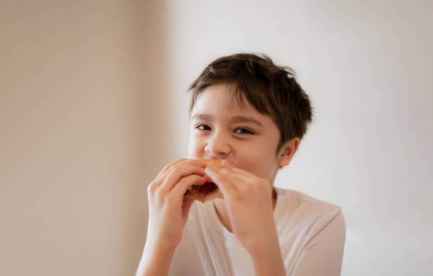 Здорова дитина їсть домашні беконні бутерброди зі змішаними овочами, щасливий молодий хлопчик снідає вдома, перш ніж піти до школи
 - Фото, зображення