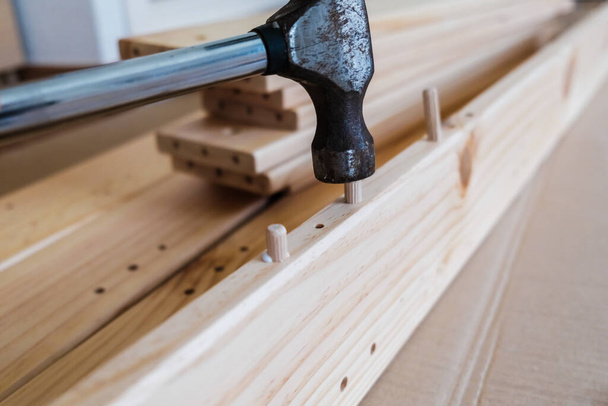 Dřevěné desky s dřevěnými hřebíky spojit kus nábytku s kladivem. - Fotografie, Obrázek