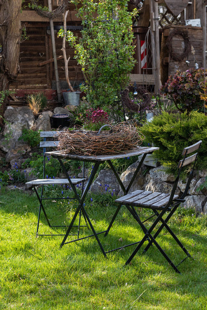  Ein blumenrotes Steinbrech-Arrangement in einem Korb steht im Garten auf einem Tisch in einem Nest - Foto, Bild