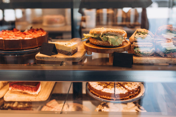 Dükkanda kekler, sandviçler ve hamur işleri olan bir vitrin. Küçük işletme, gıda konsepti - Fotoğraf, Görsel