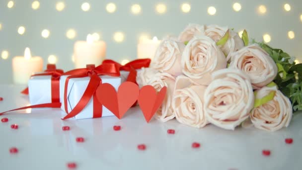 Beżowy bukiet róż, pudełka i świece na tle światła bokeh dla walentynki lub koncepcji ślubu - Materiał filmowy, wideo