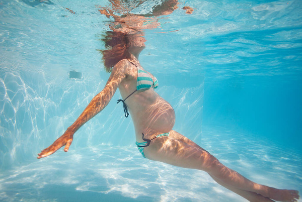 Pregnant woman with big belly exercise in outdoor pool underwater - Foto, immagini