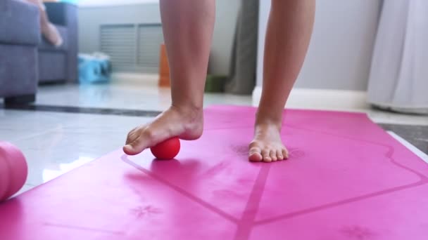 A nő egy labdával masszírozza a lábat. A labda nyomást gyakorol a fájdalmas helyre, és emeli az eljárást. - Felvétel, videó