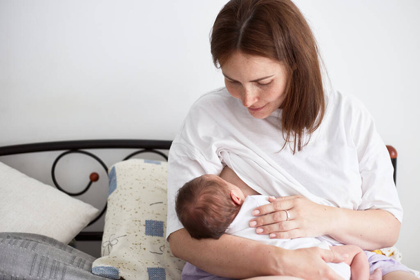 Mother breastfeeding her newborn baby boy. Realistic home portrait - Zdjęcie, obraz