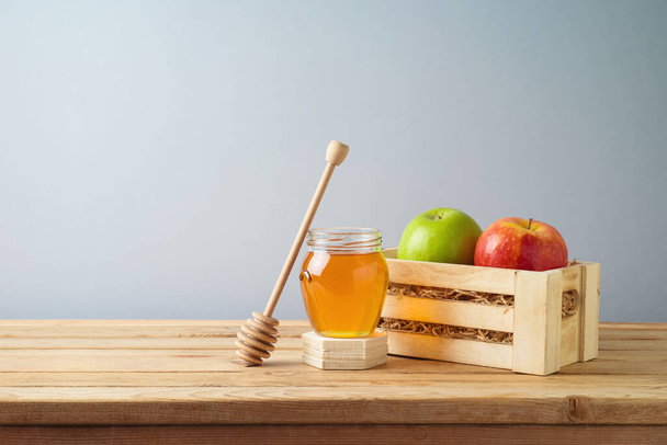 Fresh colorful apples in wooden box and honey jar on table. Greeting card background for Rosh Hashanah holiday - Valokuva, kuva