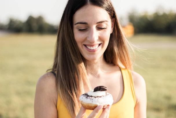 Happy woman holding donuts. Portrait of beautiful woman in meadow - Фото, изображение