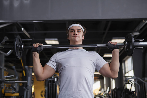 Снимок спортсмена с низкого угла, делающего упражнения на штангу - Фото, изображение