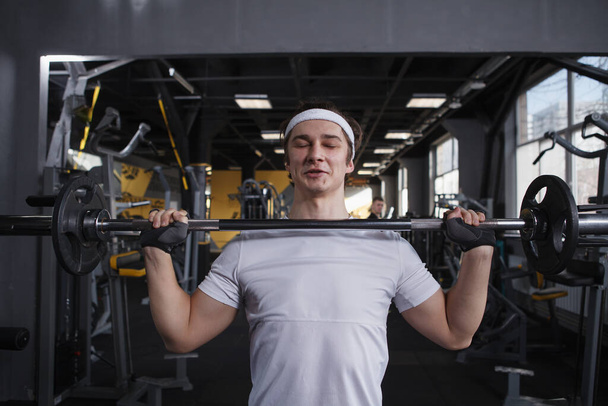 Strong healthy young man doing push press exercise with barbell - Fotoğraf, Görsel