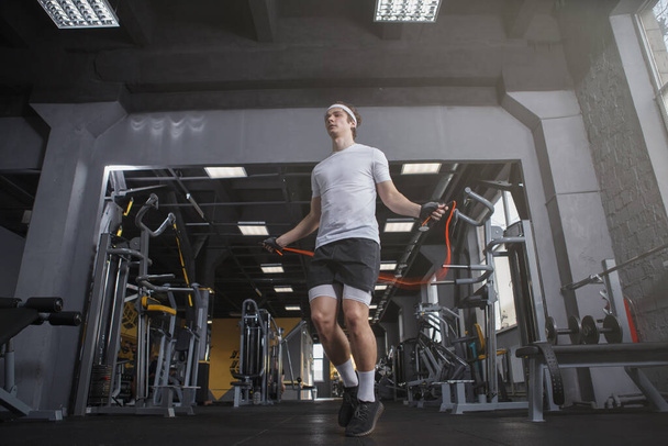 Low angle shot of a sportsman skipping on jumping rope at gym - Photo, image