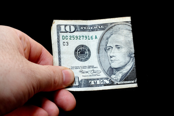Homem segurando uma nota de dez dólares, isolado em fundo preto
 - Foto, Imagem
