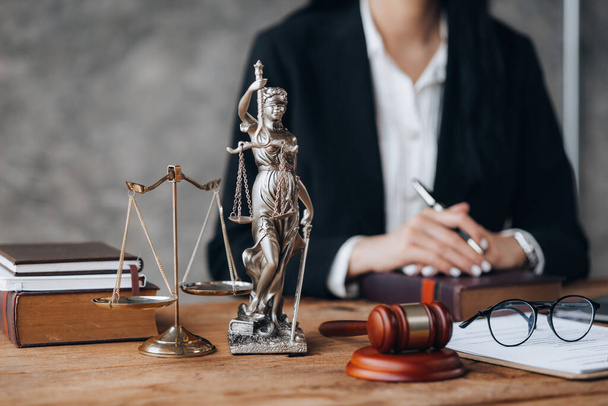 Goddess of justice and the judge's hammer are placed on the lawyer's table, lawyers consulting on various cases. To clients who are in trouble in the legal way. Lawyer concept and justice of the law. - Фото, зображення