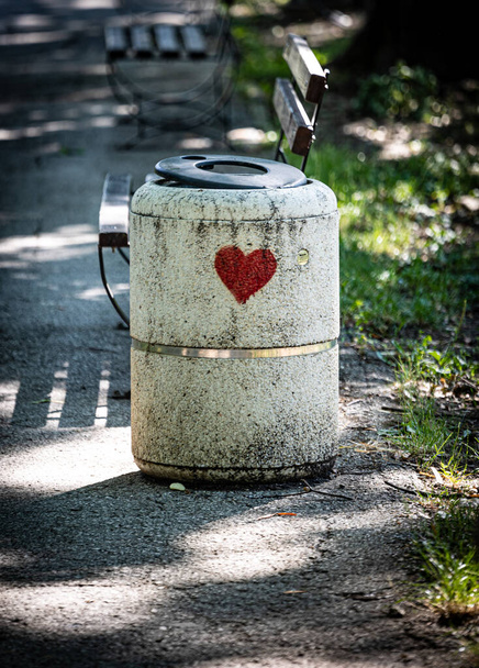 Concrete public trash can in a park stamped with red hearth symbol as a sign of appreciation for keeping surrounding area clean. - 写真・画像