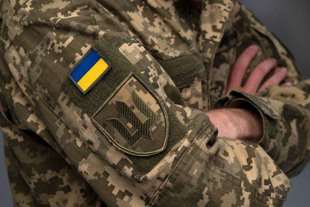 Ukrainian soldier wearing military uniform with flag and chevron depicting trident - Ukrainian emblem and national symbol - 写真・画像