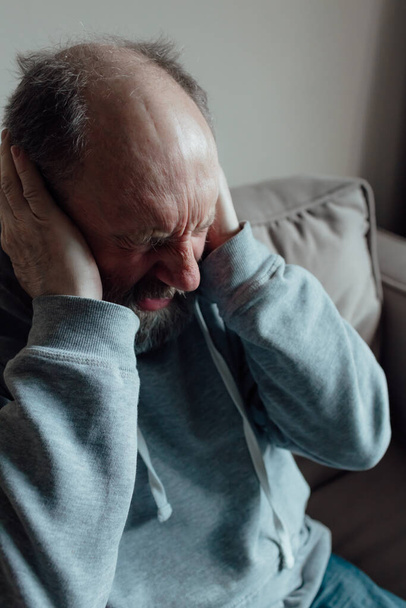 Ukrainien inquiet homme d'âge moyen a été effrayé par le bruit fort et fermé ses oreilles dans la peur. malheureux mature plus âgé grand-père à la maison. - Photo, image