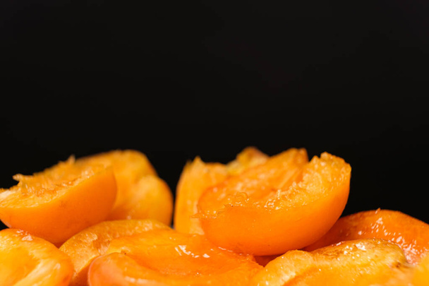 Juicy apricot slices on a black background, side view, space for text - Fotografie, Obrázek